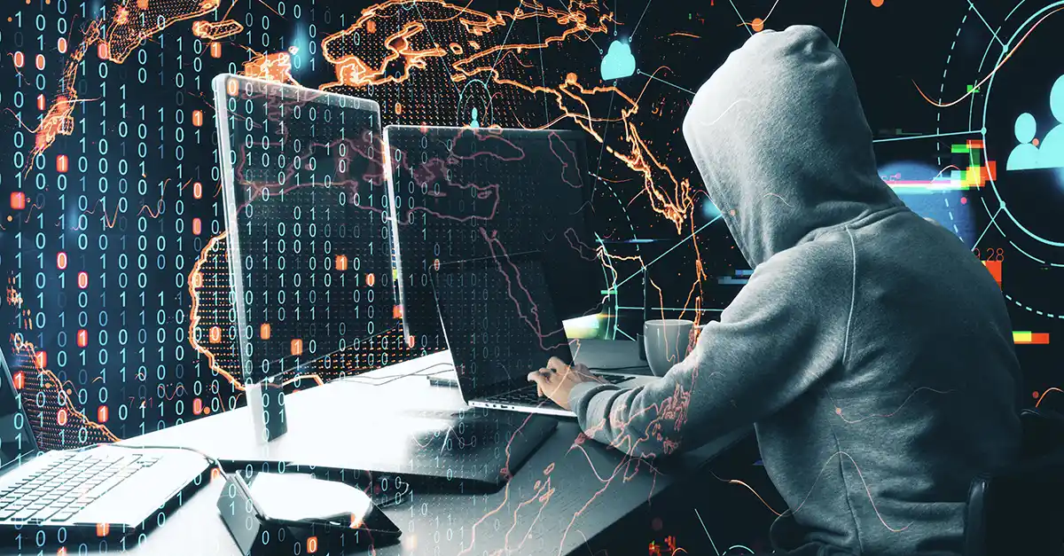 A person using multiple computer screens displaying data and network activity, representing cyber attacks and the importance of threat detection time.